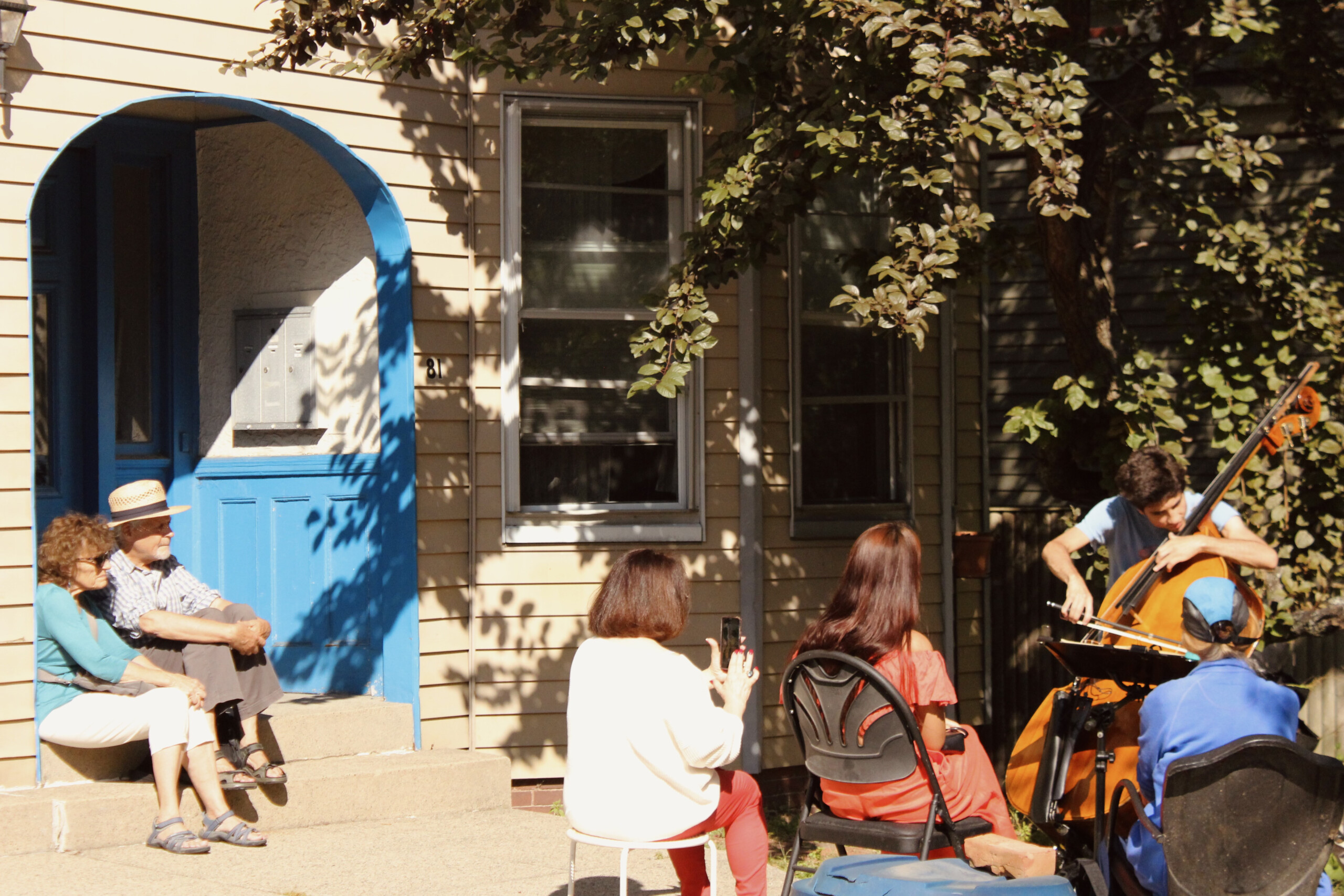 Reuben Ramos performs the cello, reading from sheet music, in front of a small but supportive crowd gathered outside 81 Francis Street. Photo by Nora Onanian