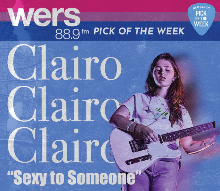 A photograph of Claire Cottrill, better known as Clairo, strumming a white electric guitar. The top third of the background has the three horizontal stripes of the bisexual pride flag (pink, purple, blue) with text that reads 