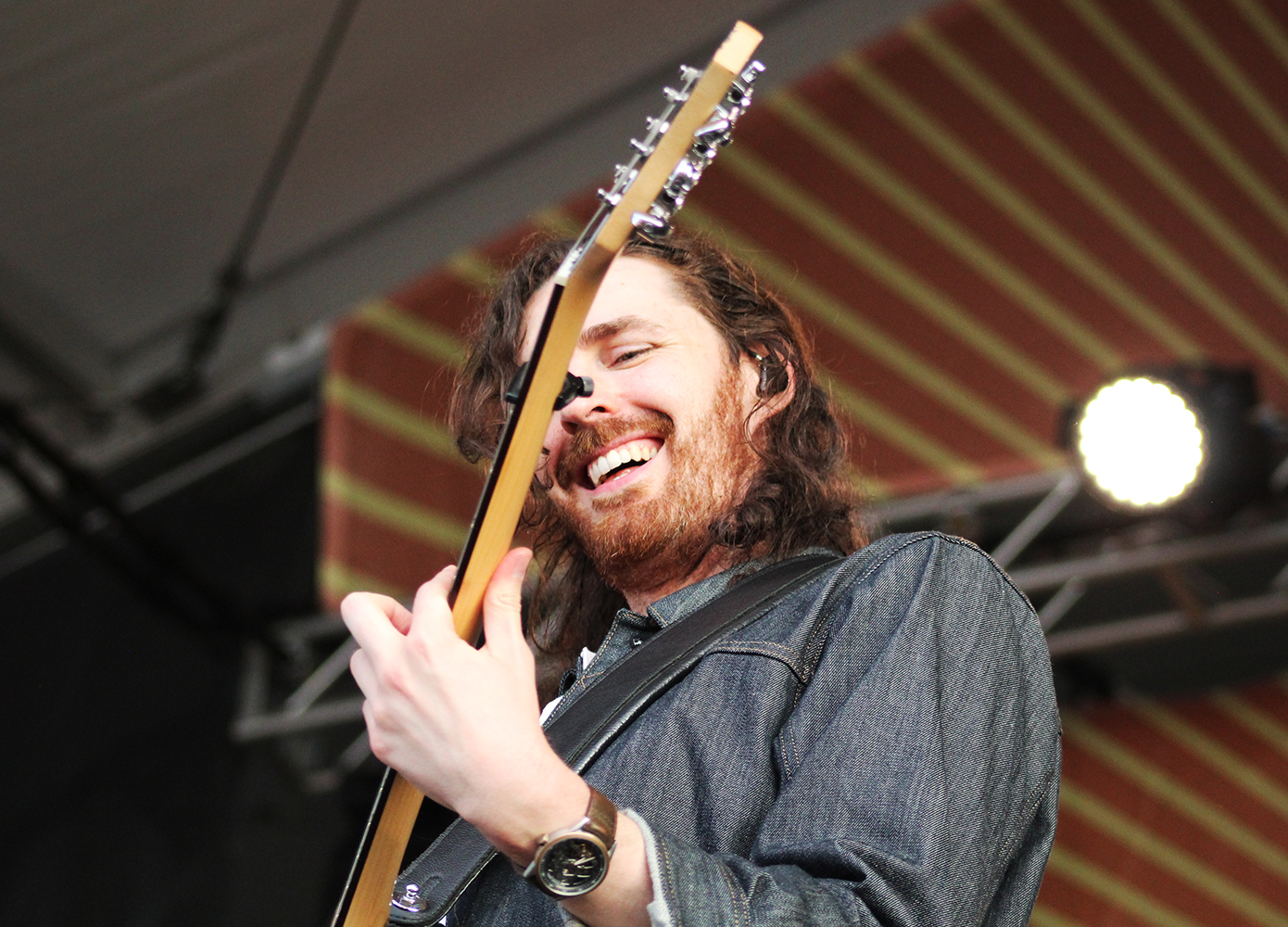 Hozier with an acoustic guitar at Newport Folk Fest, smiling.