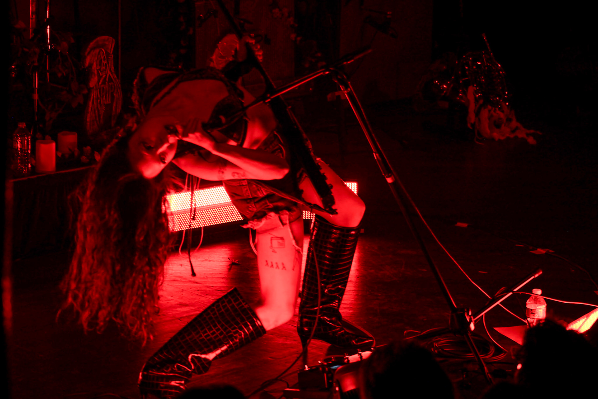 SASAMI bends backwards in front of red lighting while singing.