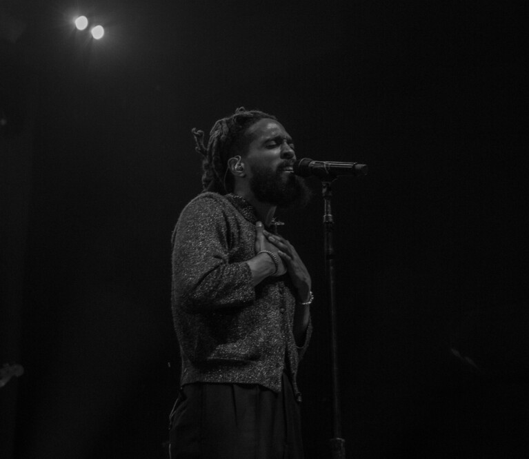 Thee Sacred Souls' lead singer stands before the mic in black and white.