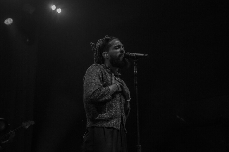 Thee Sacred Souls' lead singer stands before the mic in black and white.