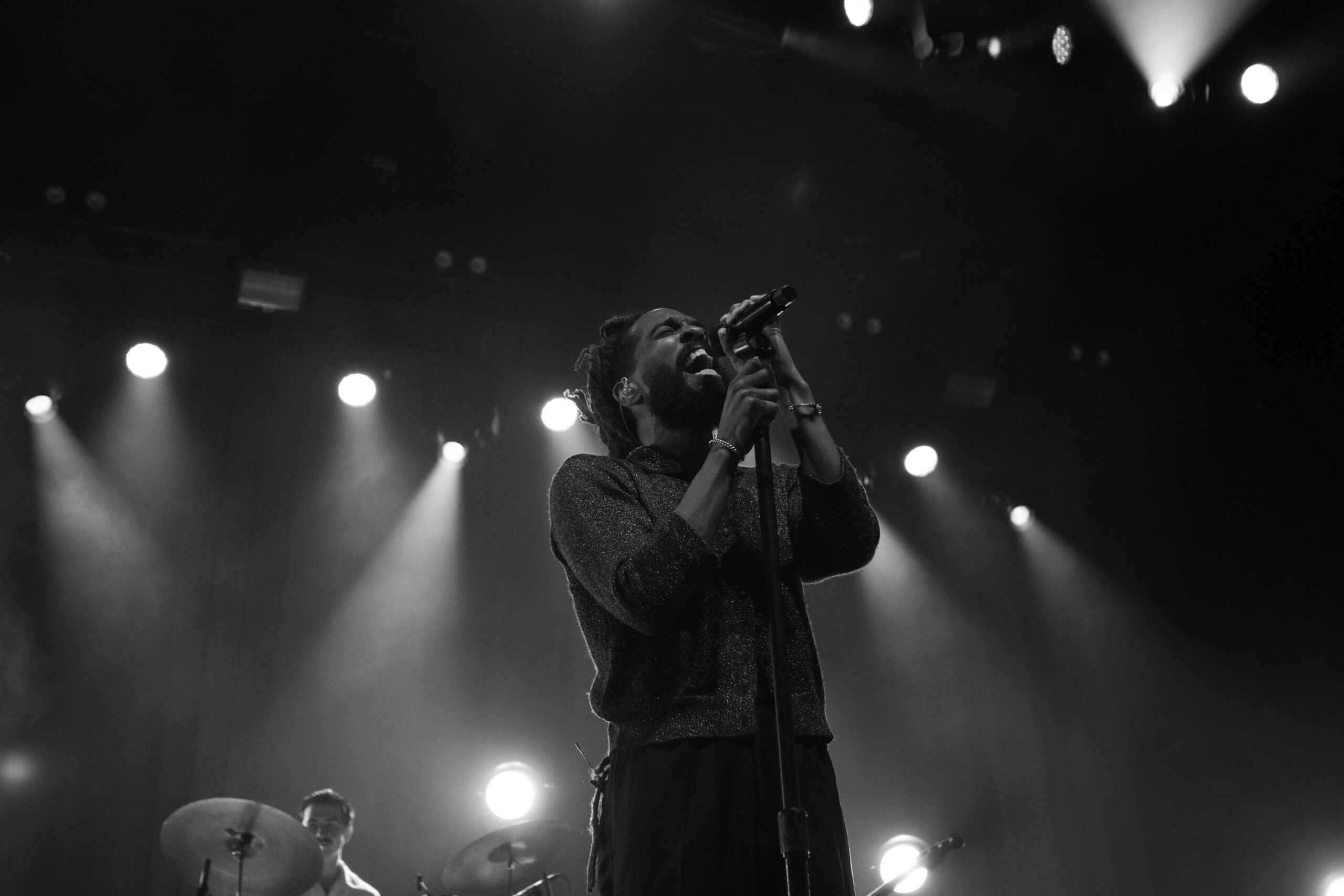 Thee Sacred Souls' lead singer stands before the mic in black and white.