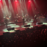 Interpol onstage with a misty blue light around them.