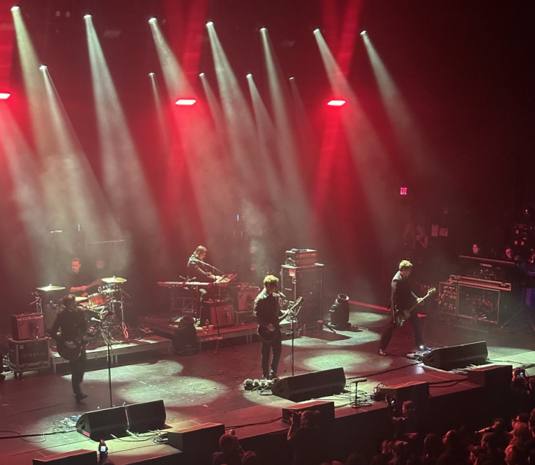 Interpol onstage with a misty blue light around them.