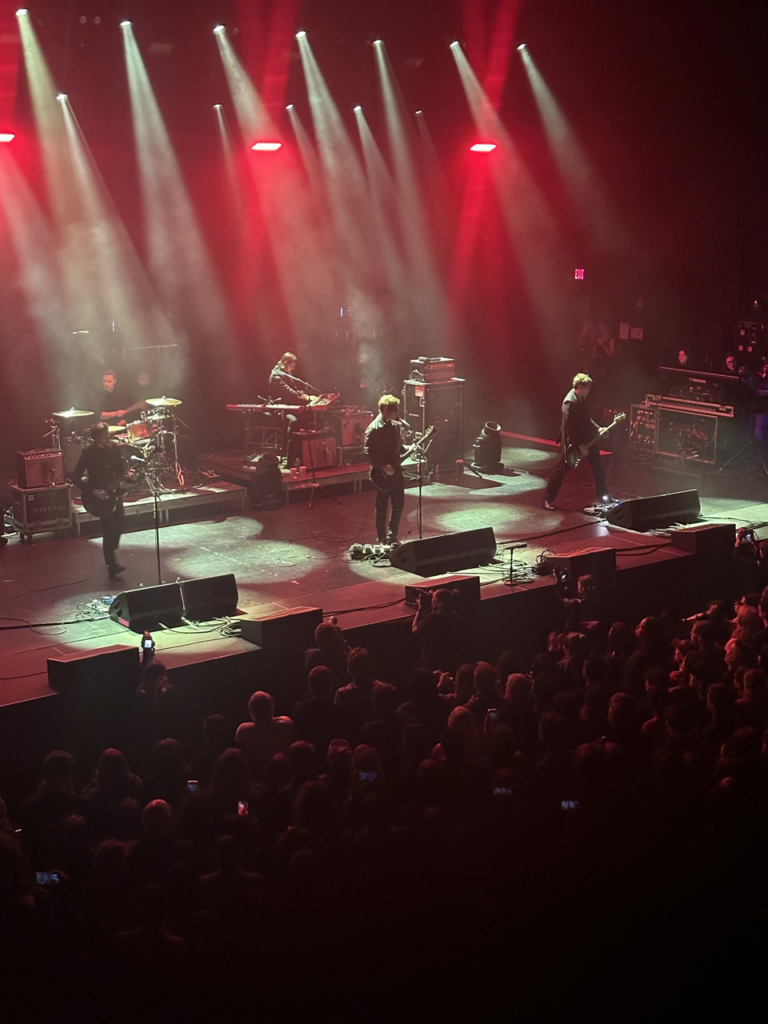 Interpol onstage with a misty blue light around them.