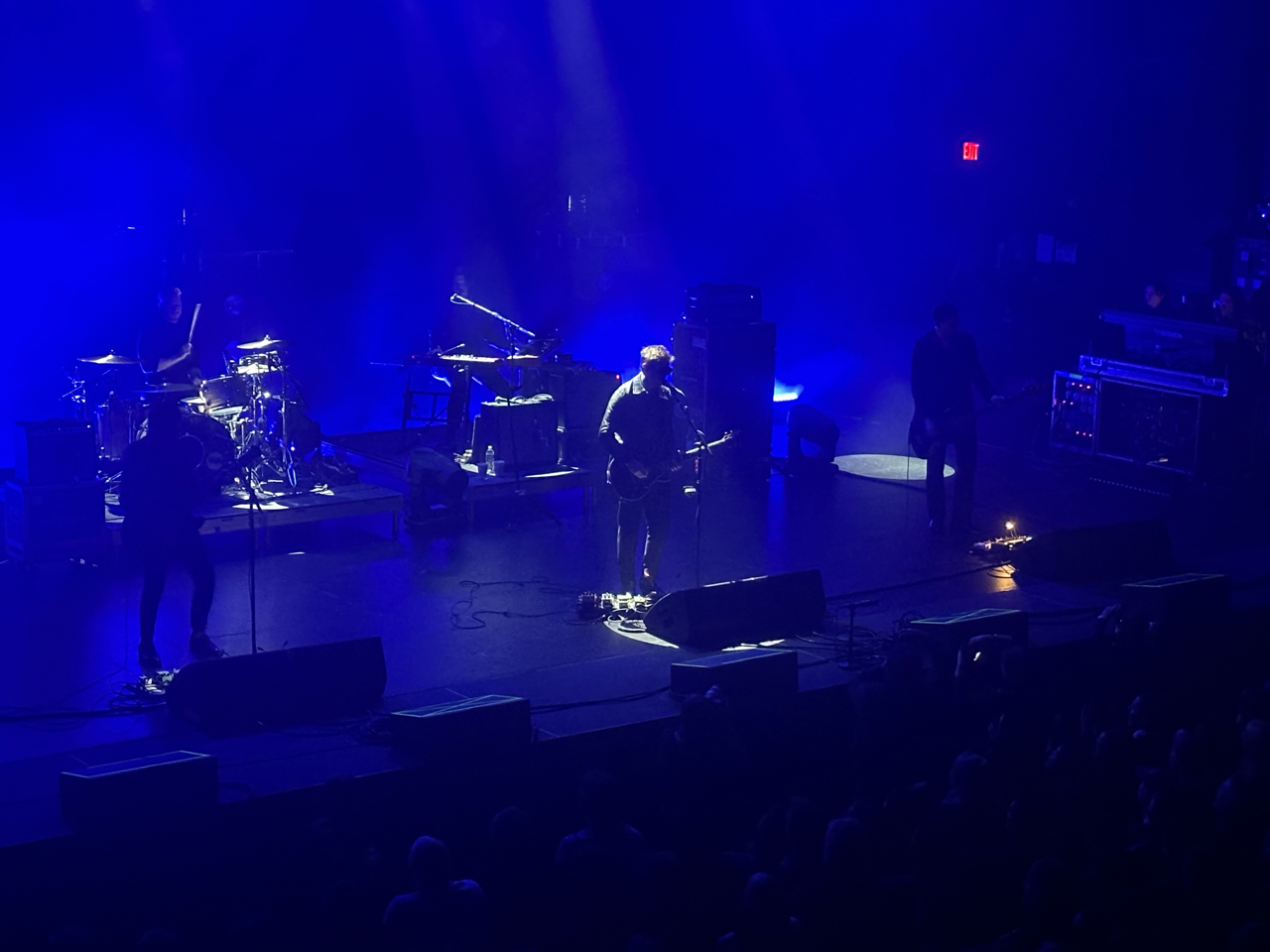 Interpol onstage with a misty blue light around them.