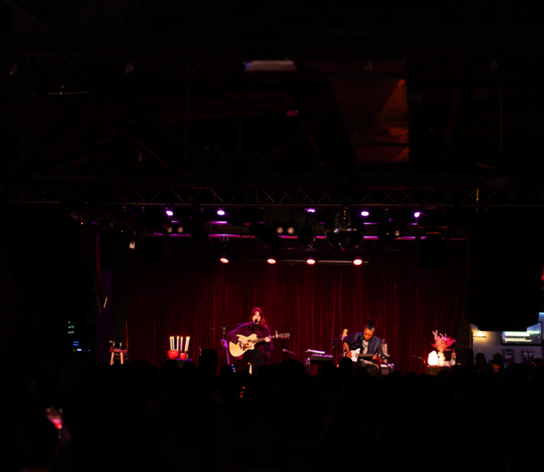 Katie Gavin plays guitar in front of red lighting at Brighton Music Hall