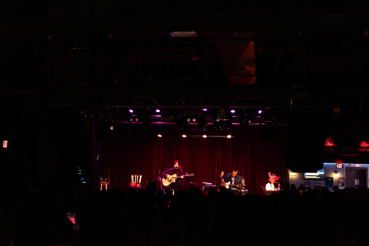 Katie Gavin plays guitar in front of red lighting at Brighton Music Hall