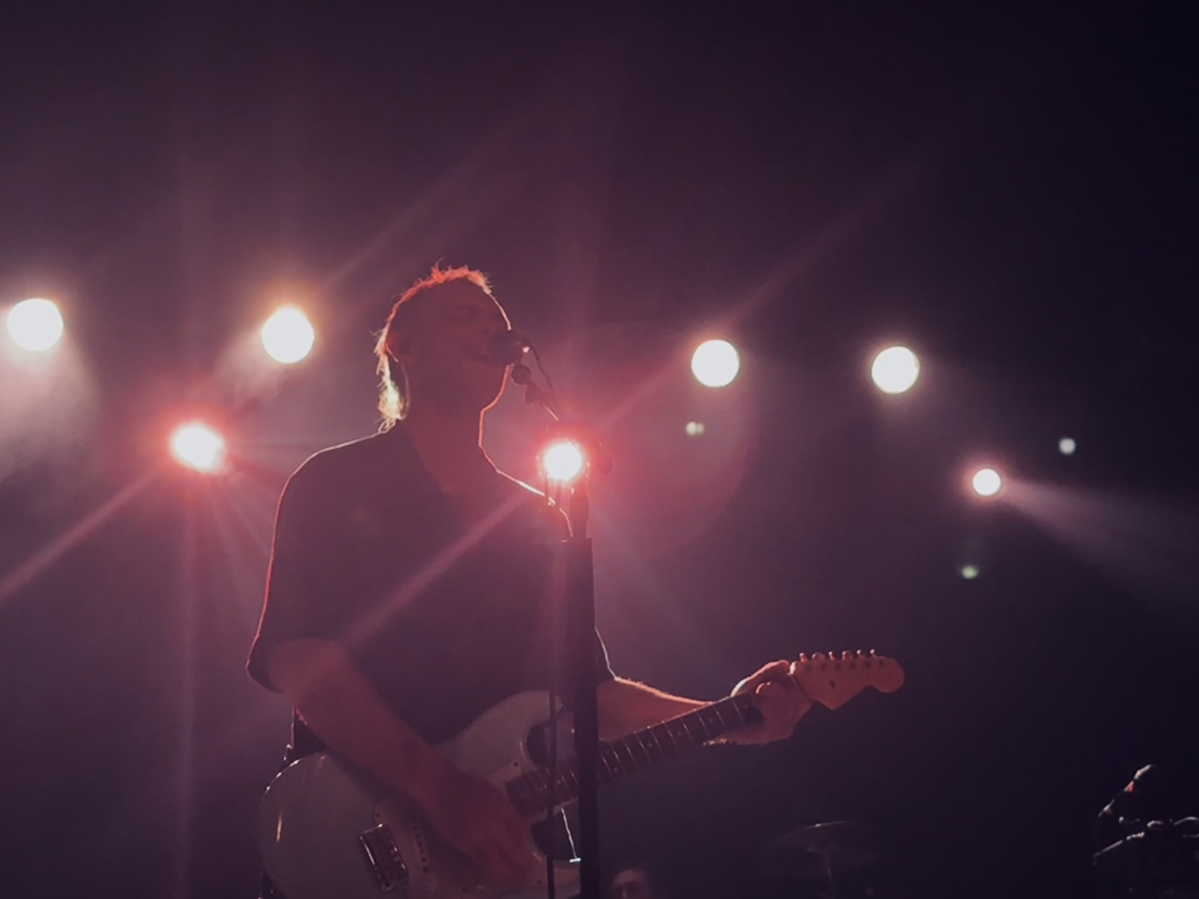 Pink lights shine behind the Wunderhorse lead guitarist.