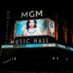 A photo of the outside of MGM Music Hall featuring Lucy Dacus on a large screen.
