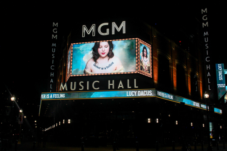 A photo of the outside of MGM Music Hall featuring Lucy Dacus on a large screen.