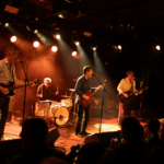 The Hard Quartet jams onstage under a warm orange light.