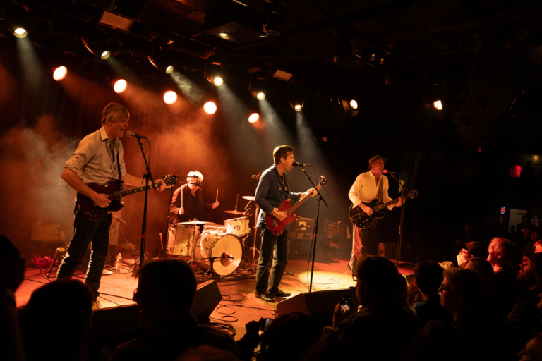 The Hard Quartet jams onstage under a warm orange light.